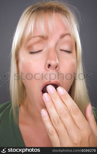 Yawning Blond Woman Against a Grey Background.