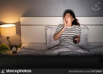 yawning sleepy woman man watching TV movie on a bed at night