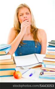 Yawning tired teen girl sitting at table with piles of books&#xA;