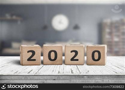 Year 2020 sign on a wooden desk in a cozy kitchen with a blurry background