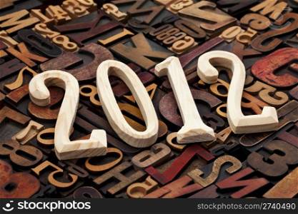 year of 2012 - wooden unfinished numbers against background of random letterpress printing blocks