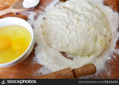 yeast dough, eggs and flour on wooden background