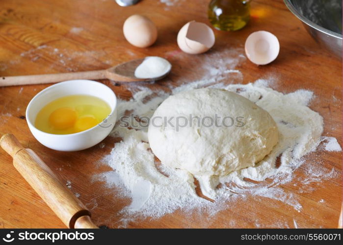 yeast dough, eggs and flour on wooden background