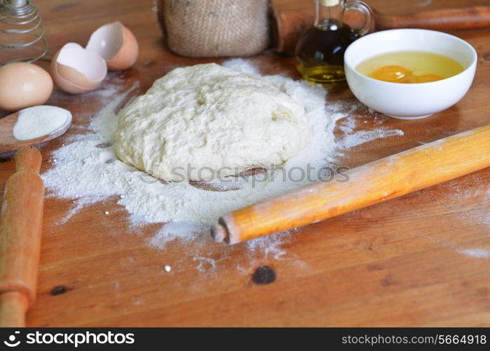 yeast dough, eggs and flour on wooden background