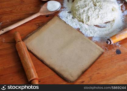 yeast dough, old sheet and flour on wooden background