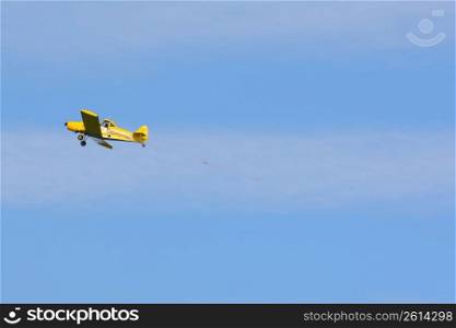 Yellow aeroplane flying through a blue sky