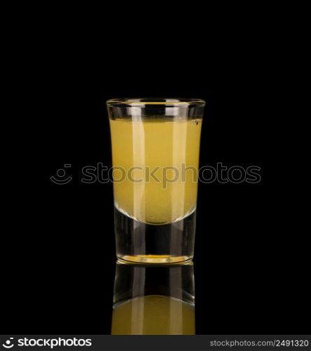 yellow alcoholic liquor in a shot glass isolated on dark background. shot glass with alcohol on a dark background
