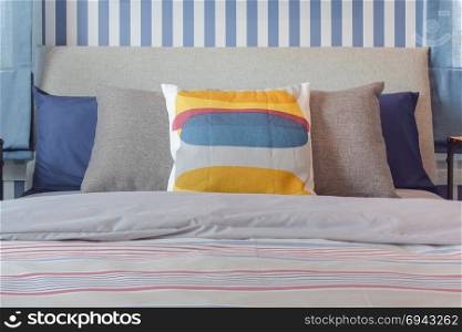 Yellow and blue graphic print pillow setting on stripe bedding bedroom