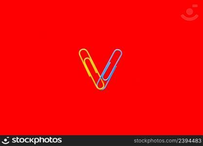 Yellow and blue paper clips on blood red background.