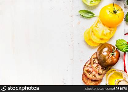 Yellow and dark red sliced tomatoes for cooking. Colorful tomatoes preparation on white wooden background, top view, place for text
