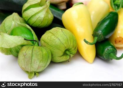 Yellow and green chili peppers with fresh tomatillos, ingredients for salsa on a white background.. Tomatillo And Chili Peppers