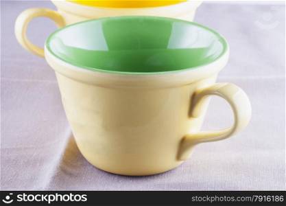 Yellow and green cup over tissue cloth, horizontal image