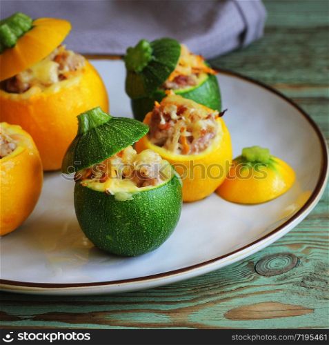 Yellow and green zucchini baked with a filling close-up on a plate. Roasted round zucchini stuffed with minced meat, vegetables, and cheese
