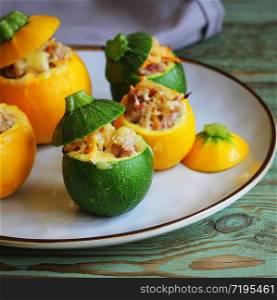 Yellow and green zucchini baked with a filling close-up on a plate. Roasted round zucchini stuffed with minced meat, vegetables, and cheese