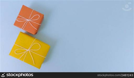 Yellow and orange gift boxes on blue background. Simple flat lay with copy space.. Yellow and orange gift boxes on a blue background. Simple flat lay with copy space.