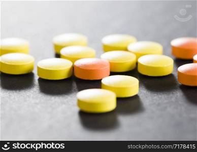 yellow and orange pills loose on a black background close-up of medical items. yellow and orange pills