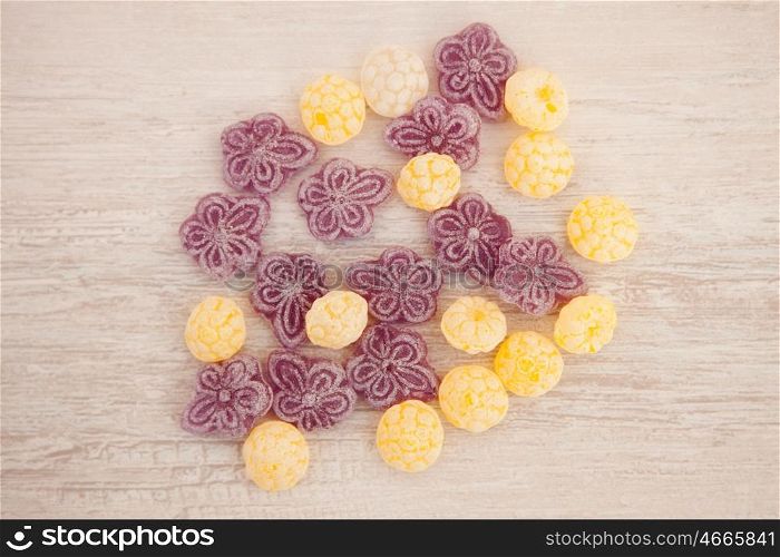 Yellow and purple candies on a gray wooden background