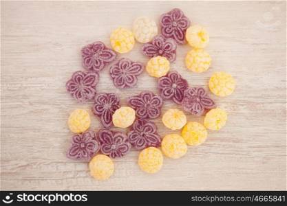 Yellow and purple candies on a gray wooden background