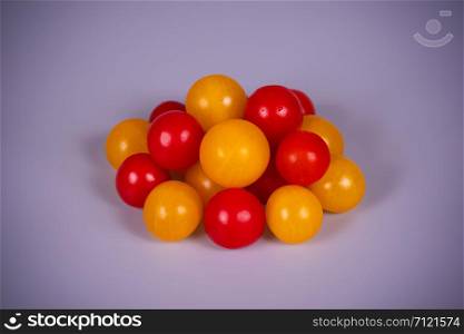 Yellow and red cherry tomatoes on a gray background.