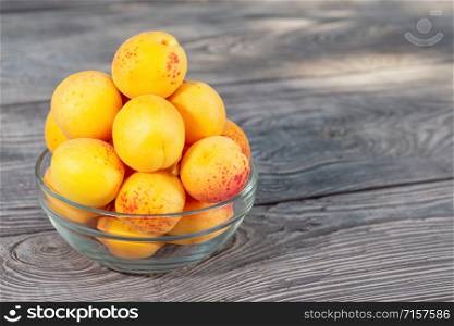 Yellow apricots in a glass bowl on a wooden table. Yellow apricots in glass bowl on wooden table