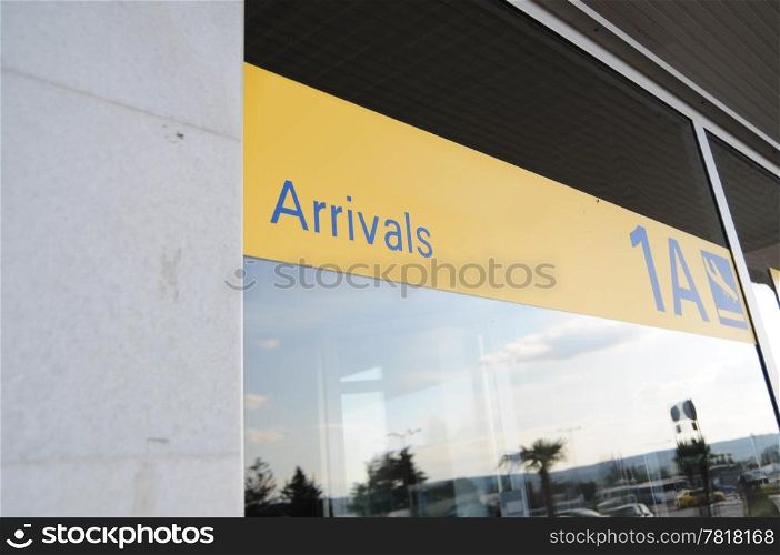 Yellow arrivals sign on outside of an airport