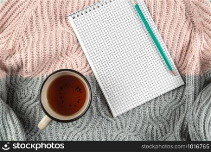 yellow autumn leaves, a Cup of tea and a notebook on a textured sweater with empty space for text. the view from the top. flat lay