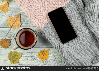 yellow autumn leaves, a Cup of tea and a smartphone on an old wooden background with empty space for text. the view from the top. flat lay