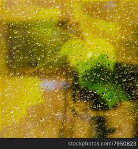 yellow background from raindrops on window pane during night rain