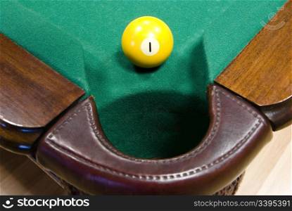 "yellow billiard ball with number "one" in front of corner pocket on green baize table "
