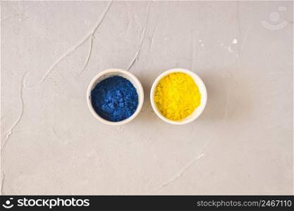 yellow blue holi color powder white bowls concrete background