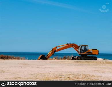 Yellow bulldozer working on a beach with copy space.. Yellow bulldozer working on a beach with copy space