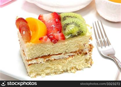 Yellow cake with fruit glaze and fresh strawberry, kiwi, grape and peach on top.