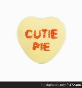 Yellow candy heart that reads cutie pie against white background.