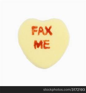 Yellow candy heart that reads fax me against white background.
