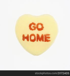 Yellow candy heart that reads go home against white background.