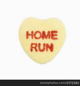 Yellow candy heart that reads home run against white background.