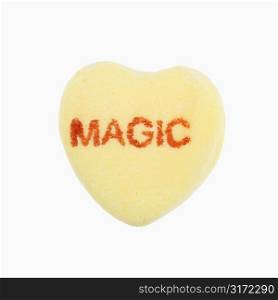 Yellow candy heart that reads magic against white background.