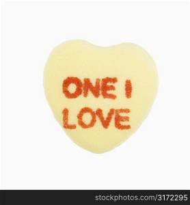 Yellow candy heart that reads one I love against white background.