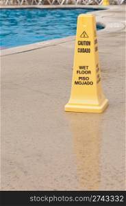 yellow caution sign regarding slippery surface next to a swimming pool (after a tropical storm)