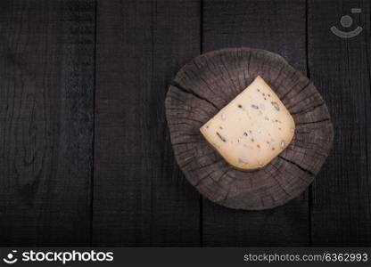yellow cheese with seeds on a wooden end of a tree