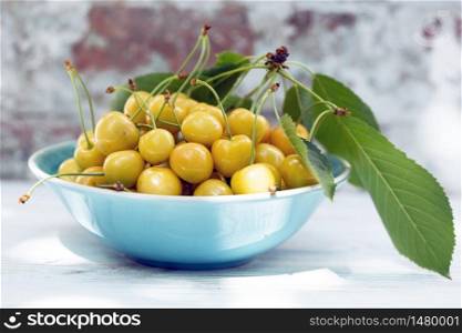 Yellow cherry in a bowl on the table in the garden