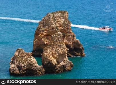 Yellow cliff near coast (Ponta da Piedade, Algarve, Portugal). All people in motorboat are unrecognizable.