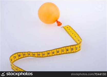 Yellow color measuring tape and a balloon on a white background