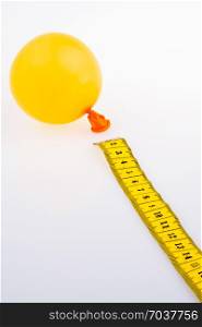 Yellow color measuring tape and a baloon on a white background