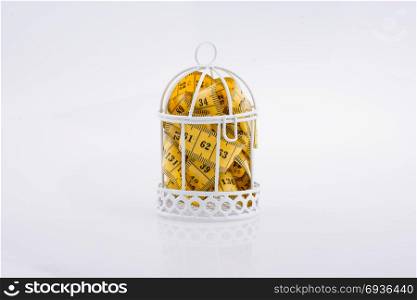 Yellow color measuring tape in a cage on a white background