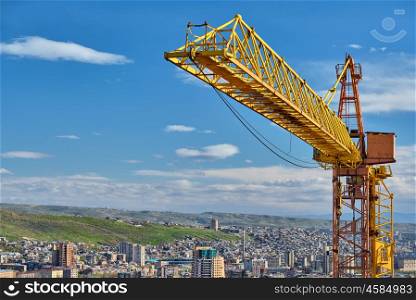 Yellow construction jib crane tower against blue sky