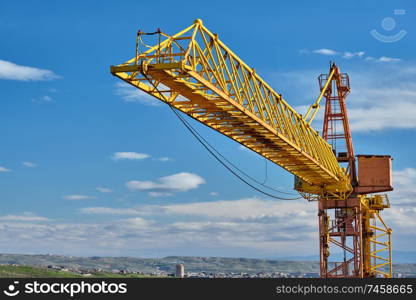Yellow construction jib crane tower against blue sky