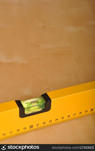 yellow construction level on a brown wooden background