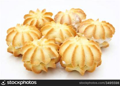 Yellow cookies with a white stuffing lie on a white background in the form of a circle