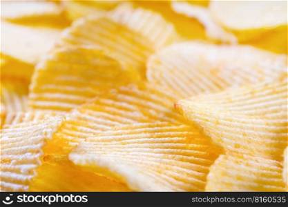 Yellow crispy ridged potato chips close up. Food background, banner, header, wallpaper.